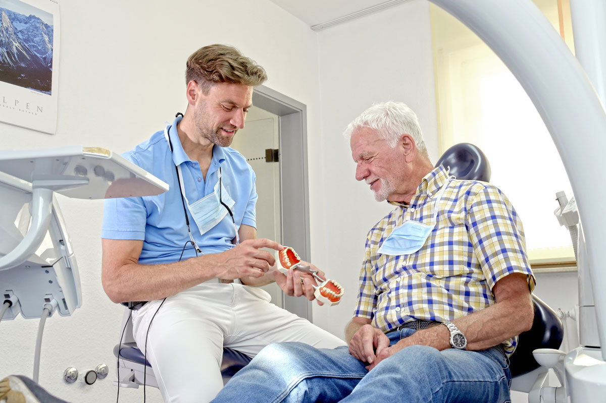 Zahnarzt erklärt Patienten Details anhand eines Modells